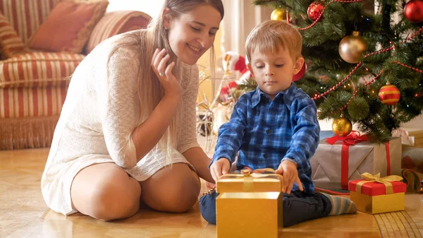 Jovem mãe feliz e filho da criança estão animados com presentes de Natal — Fotografia de Stock