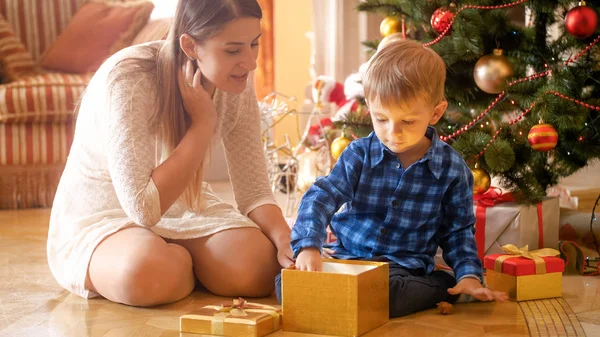 Pequeño niño de 3 años abre caja de regalo de Navidad y saca un juguete — Foto de Stock