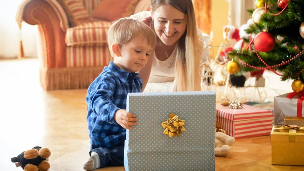 Porträtt av glada leende familj med liten pojke öppna julklappar — Stockfoto