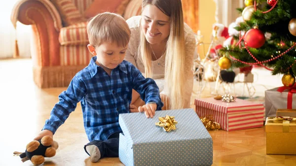 Lindo niño pequeño abriendo y mirando dentro de la caja de regalo de Navidad — Foto de Stock