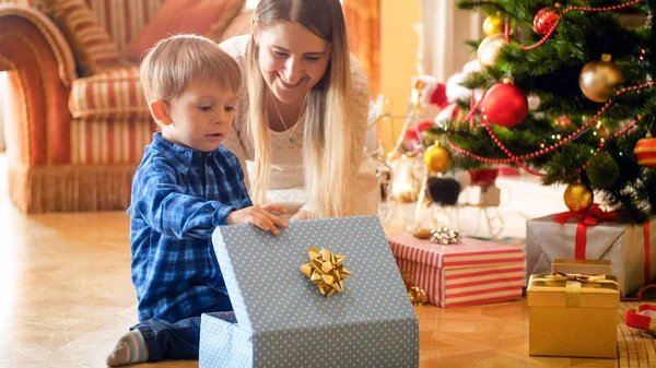 Chłopak ładny maluch patrząc wewnątrz Christmas gift box z młoda matka — Zdjęcie stockowe