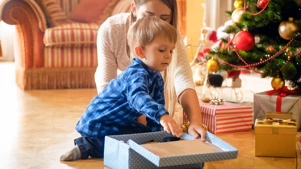 Niño de 3 años recibiendo regalo de Navidad bajo el árbol de Navidad por la mañana — Foto de Stock