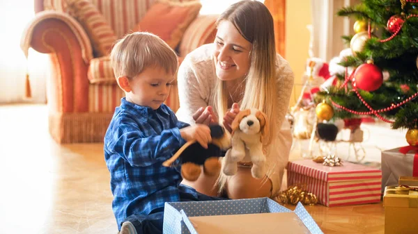 Симпатичный мальчик с матерью, радующийся рождественским подаркам и подаркам от Санты — стоковое фото