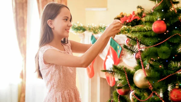 Retrato de hermosa chica sonriente poniendo decoraciones en el árbol de Navidad — Foto de Stock