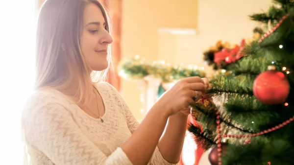 Portrét krásné mladé ženy zdobí vánoční stromeček v obýváku — Stock fotografie