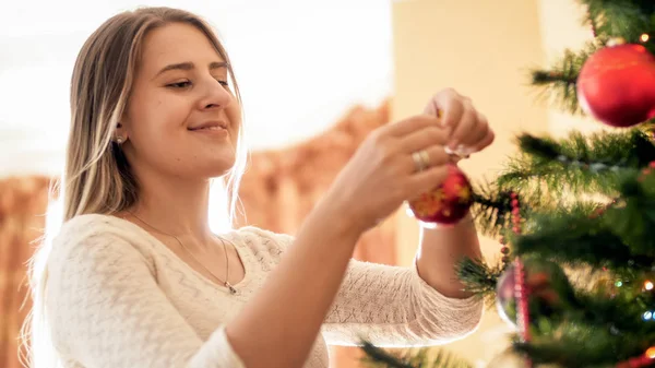 Portrait de belle femme souriante suspendue boules rouges sur l'arbre de Noël — Photo