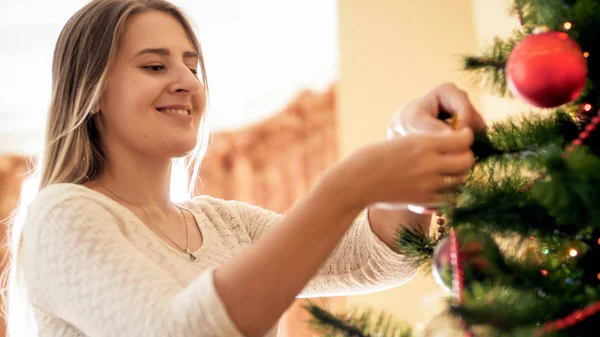 つまらないものとビーズのクリスマス ツリーを飾る若い女性のポートレート クローズ アップ — ストック写真