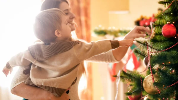 Porträtt av glada leende ung mamma dekorera julgran med hennes lille son — Stockfoto