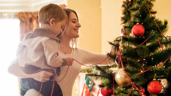 Tónusú segít az anyja karácsonyfa díszítő kisfiú portréja — Stock Fotó
