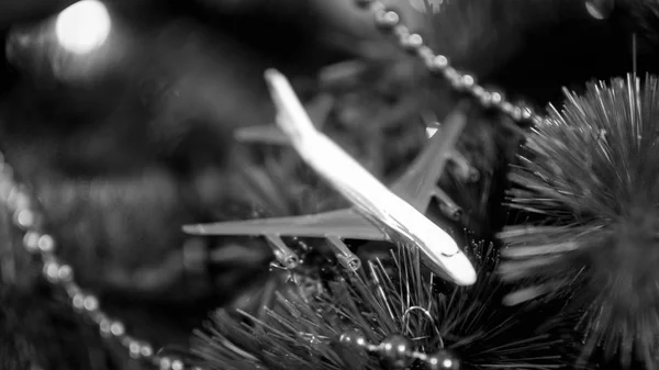 Black and white closeup image of toy airplane lying on Christmas tree branches. Concept of winter holidays travelling — Stock Photo, Image