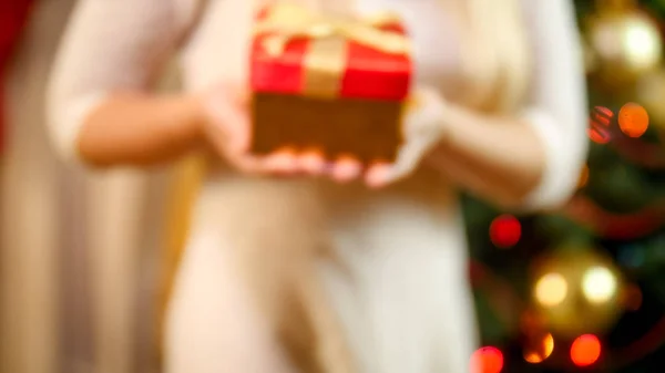 Wazig uit focus foto van vrouw met de doos van de gift tegen kerstboom — Stockfoto