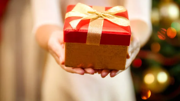 Imagem close-up de jovem mulher em vestido mostrando caixa de presente vermelho na câmera. Conceito de presentes de Natal — Fotografia de Stock