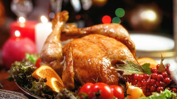 Close-up beeld van lekkere gebakken kip tegen gloeiende lichten van Kerstmis en het branden van kaarsen — Stockfoto
