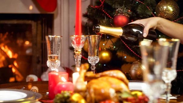 Imagem de close-up de encher copos com champanhe no jantar de família ao lado da árvore de Natal e lareira em chamas — Fotografia de Stock