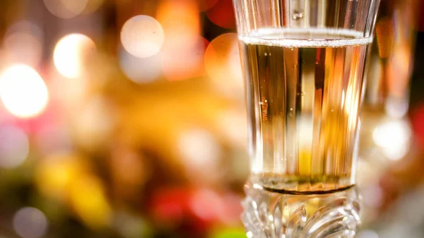 Detailní snímky šampaňského naplněné sklo proti zářící barevné vánoční osvětlení — Stock fotografie