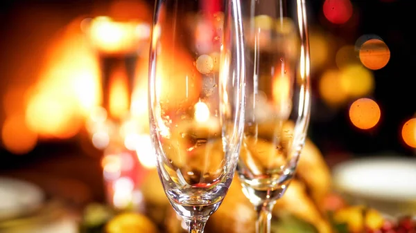 Imagen de primer plano de las copas de champán vacías contra la chimenea ardiente y el brillante árbol de Navidad —  Fotos de Stock