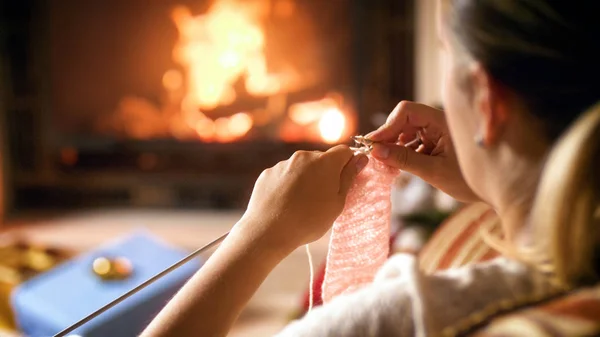 Closeup image of young woman sitting bu the fireplace and knitting woolen jumper — Stock Photo, Image