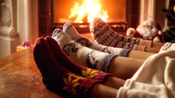 Closeup image of family in knitted woolen socks warming by fireplace — Stock Photo, Image