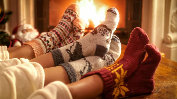 Family wearing knitted woolen socks warming feet at fireplace on Christmas eve — Stock Photo, Image