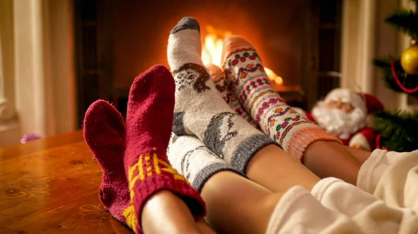 Vértes tónusú kép család kötött zokni karácsony estéjén a kandalló mellett felmelegedés — Stock Fotó