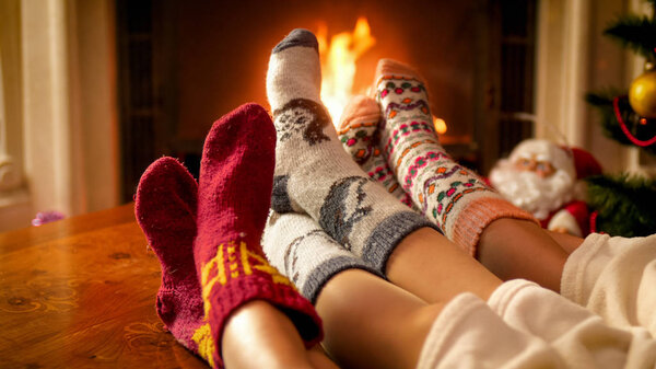 Closeup photo of parents qith child warming by the fireplace on cold winter day