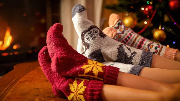 Closeup image of family in warm knitted socks lying next to fireplace and Christmas tree — Stock Photo, Image