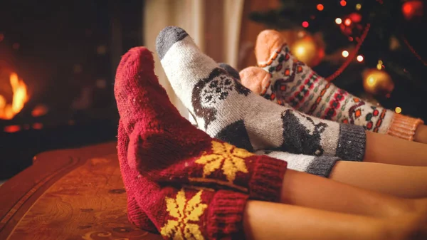Közelkép kép család gyapjú zokni pihentető mellett a kandalló tónusú karácsony estéjén — Stock Fotó