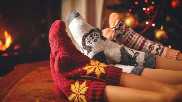 Toned closeup image of family in woolen socks relaxing by the fireside on Christmas eve