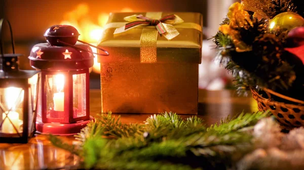 Closeup image of Christmas gift and magic lanterns against burning fireplace — Stock Photo, Image