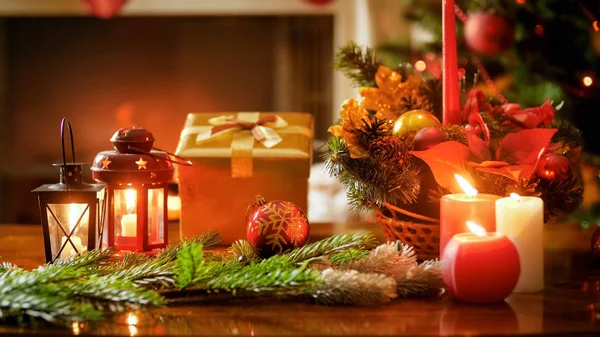 Крупный план фото горящих свечей, подарочная коробка и рождественский венок на деревянном столе — стоковое фото