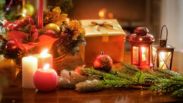 Closeup image of candles on lanterns next Christmas gifts and wreath — Stock Photo, Image