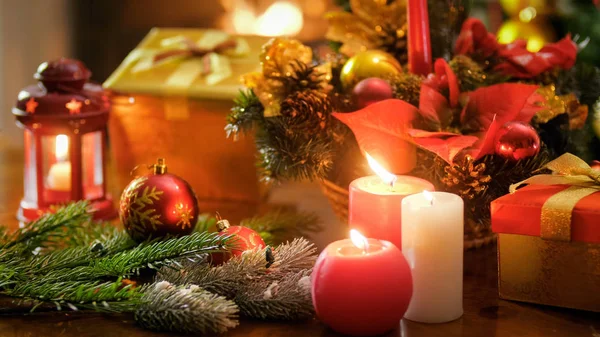 Detailní obraz hořící svíčky proti vánoční dekorace a dárkové krabičky — Stock fotografie
