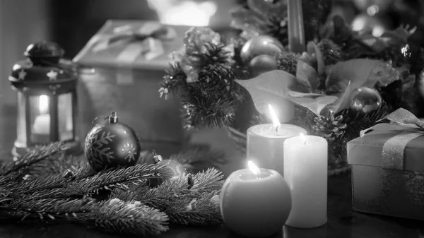 Svartvit bild av vackra juldekorationer och ljusen på träbord — Stockfoto