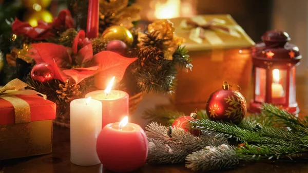 Κοντινό πλάνο εικόνα του τρία κεριά καύση σε ξύλινο τραπέζι ενάντια φυσαλίδες, κουτιά δώρων και χριστουγεννιάτικο δέντρο — Φωτογραφία Αρχείου