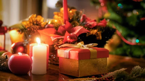 Detailní Foto svíčky a dárky na dřevěný stůl proti vánoční strom — Stock fotografie