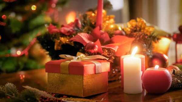 Closeup image of Santas present in red box on wooden table against Christmas tree — Stock Photo, Image