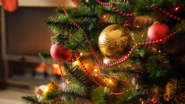 Närbild bild av dekorerad glänsande julgran mot brinnande eld i öppna spisen — Stockfoto