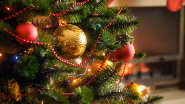 Image rapprochée de branches d'arbre de Noël décorées contre cheminée en feu dans le salon de la maison — Photo