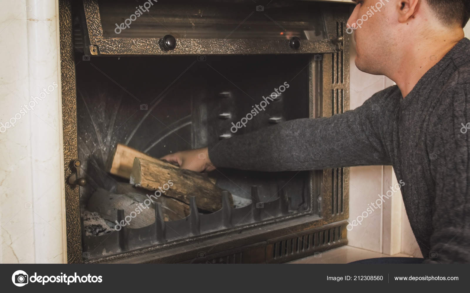Portrait Of Young Man Throwing Wooden Logs In Fireplace At Living
