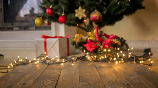 Perfekte Kulisse für Weihnachts- und Winterfeiern. Holztisch gegen geschmückten Weihnachtsbaum und leuchtende bunte Lichter — Stockfoto