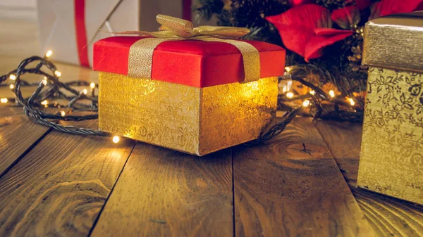 근접 촬영 톤의 빛나는 크리스마스 조명에 대 한 나무 책상에 선물 황금 상자 이미지 — 스톡 사진