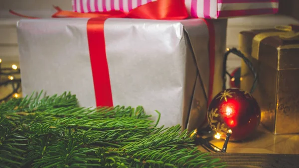 Closeup tonificado imagem de grande caixa de presente com fita vermelha na mesa de madeira ao lado de decorações de Natal — Fotografia de Stock