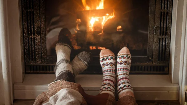 Nahaufnahme eines romantischen Paares in warmen Wollsocken, die sich am Feuer im Haus wärmen — Stockfoto