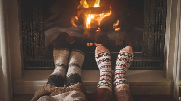 Toned closeup image of man and woman wearing woolen socks and lying by the fireplace — Stock Photo, Image