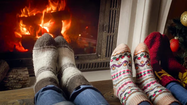 Foto de cerca de tres personas en calcetines de lana calentándose en la chimenea — Foto de Stock