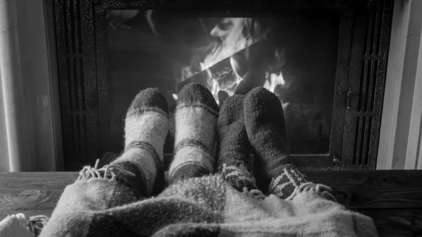 Black and white image of couple lying at burning fireplace in living room — Stock Photo, Image