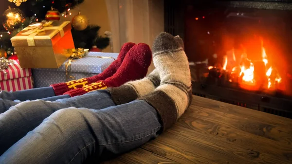 Imagen de primer plano de la pareja con calcetines de lana relajándose junto a la chimenea en la víspera de Navidad — Foto de Stock