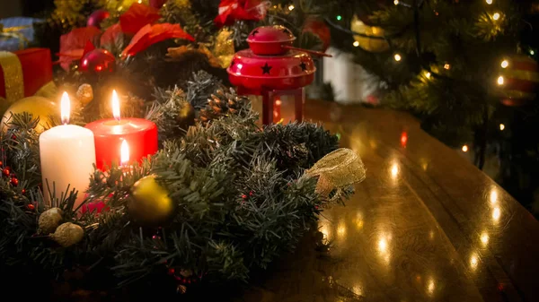 Detailní snímky dekorativní věnec, lucernu a hořící svíčky na dřevěný stůl proti zářící vánoční osvětlení — Stock fotografie
