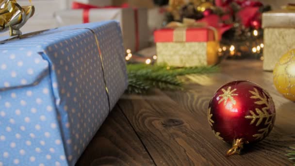 Closeup 4k πλάνα από κάμερα panning πάνω από τα δώρα Χριστουγέννων και πολύχρωμα στολίδια στο πάτωμα — Αρχείο Βίντεο
