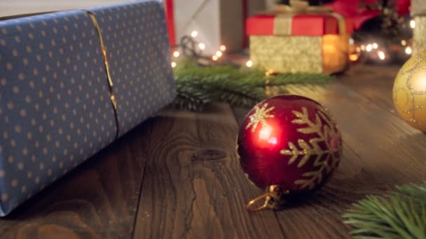 Schwenk-4k-Video von bunten Kugeln und Weihnachtsgeschenken auf Holzgrund — Stockvideo